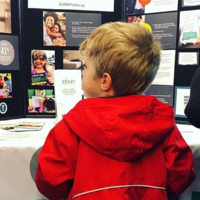 A young boy stands at a table of Be SMART information
