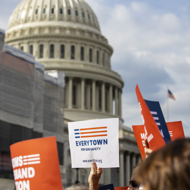 An Everytown for Gun Safety sign is held in the air in a crowd of people