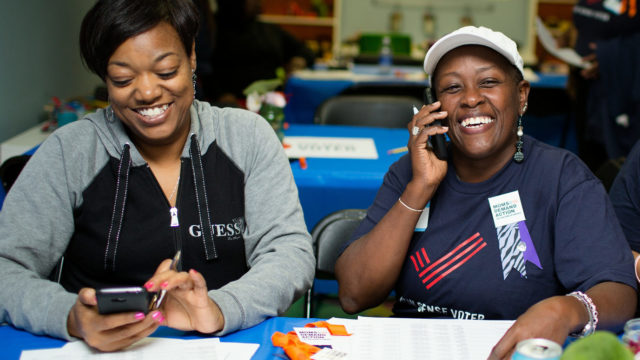 Two volunteers smile as they volunteer at a phonebank