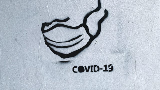 A mask and COVID-19 are spray painted on a wall