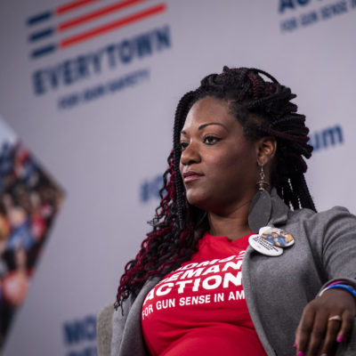 DeAndra Dycus a Moms Demand Action volunteer and survivor of gun violence sits in a chair on the stage at the Gun Sense Forum in 2019