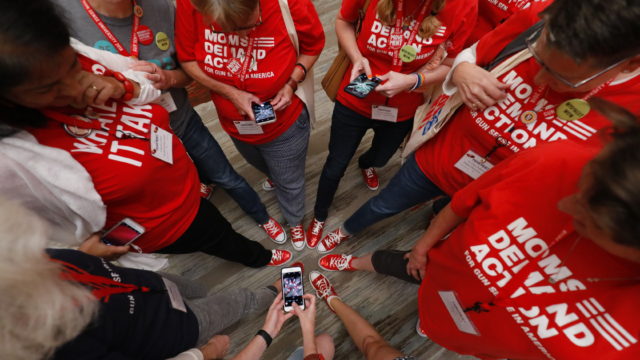 A group of Moms Demand Action volunteer stand in a circle while taking a photo of their matching shoes