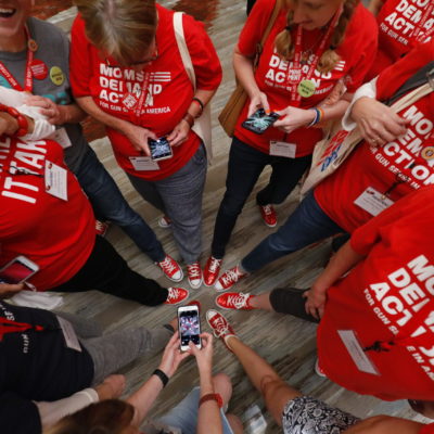 A group of Moms Demand Action volunteer stand in a circle while taking a photo of their matching shoes