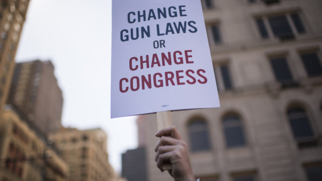 protestor holding a change gun laws or change congress sign
