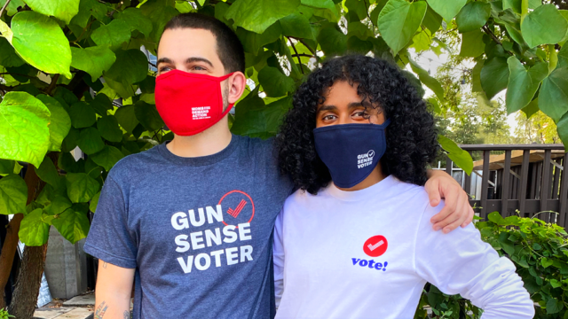 Two people stand together while wearing Gun Sense Voter merchandise