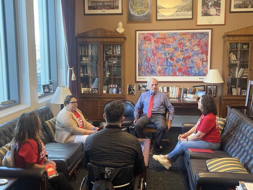Four California volunteers speak with Rep. Mark DeSaulnier in his office. Three of the volunteers sit on the couches and are turned toward DeSaulnier, who is in a chair in between the couches. A fourth volunteer sits in his wheelchair directly across from DeSaulnier.