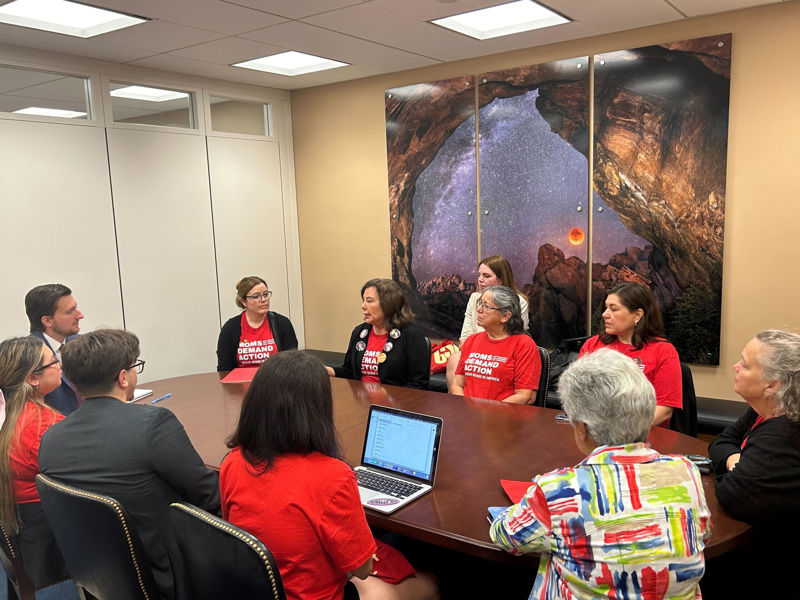 Ten volunteers from New Mexico meet with Sen. Martin Heinrich and his staff. They sit in a circle around an oval brown wood table.