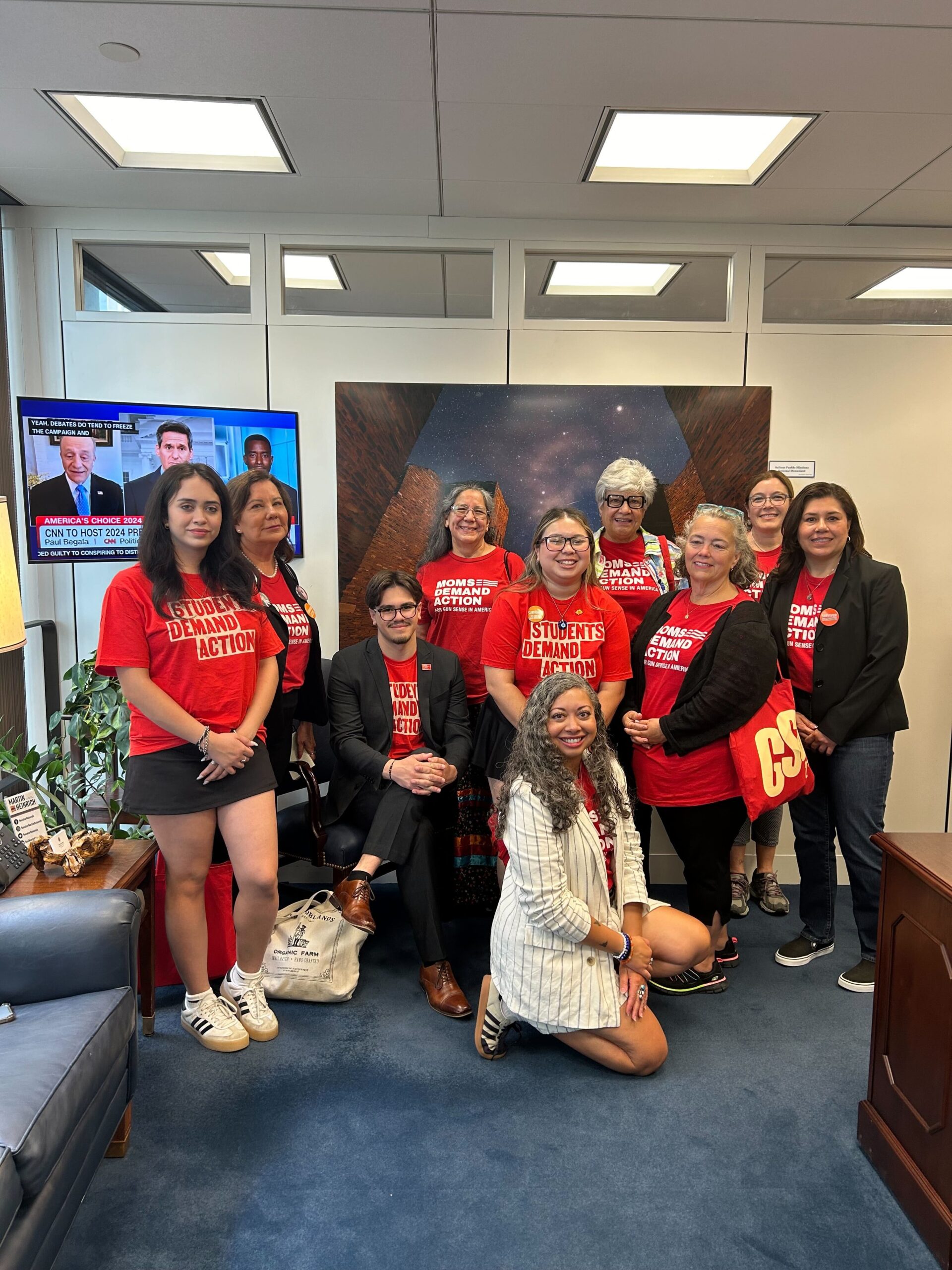 Ten volunteers from New Mexico pose in the waiting area of Sen. Heinrich's office. They all wear red Moms Demand Action and Students Demand Action shirts. 