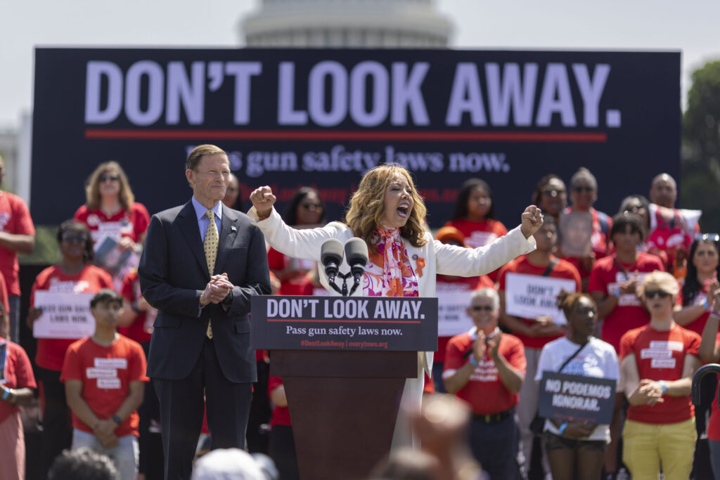 Rep. Lucy McBath speaks animatedly at a podium during a 2022 "Don't Look Away" awareness campaign and event in front of the U.S Capitol Building.